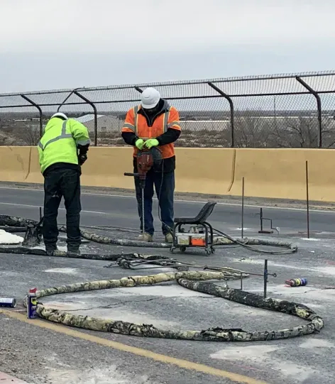 Two technicians performing URETEK Deep Injection near runway